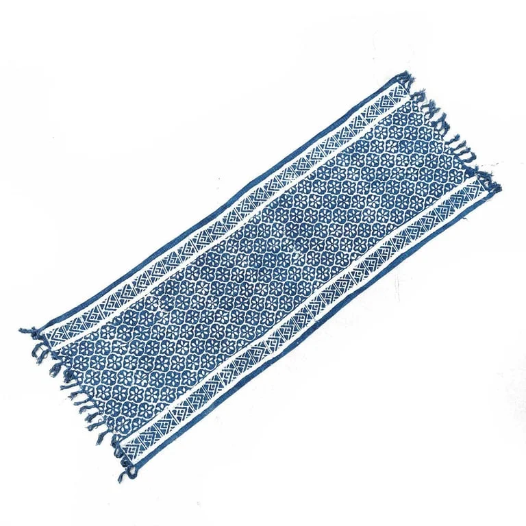 Handmade indigo table runner draped on a wooden tabletop.