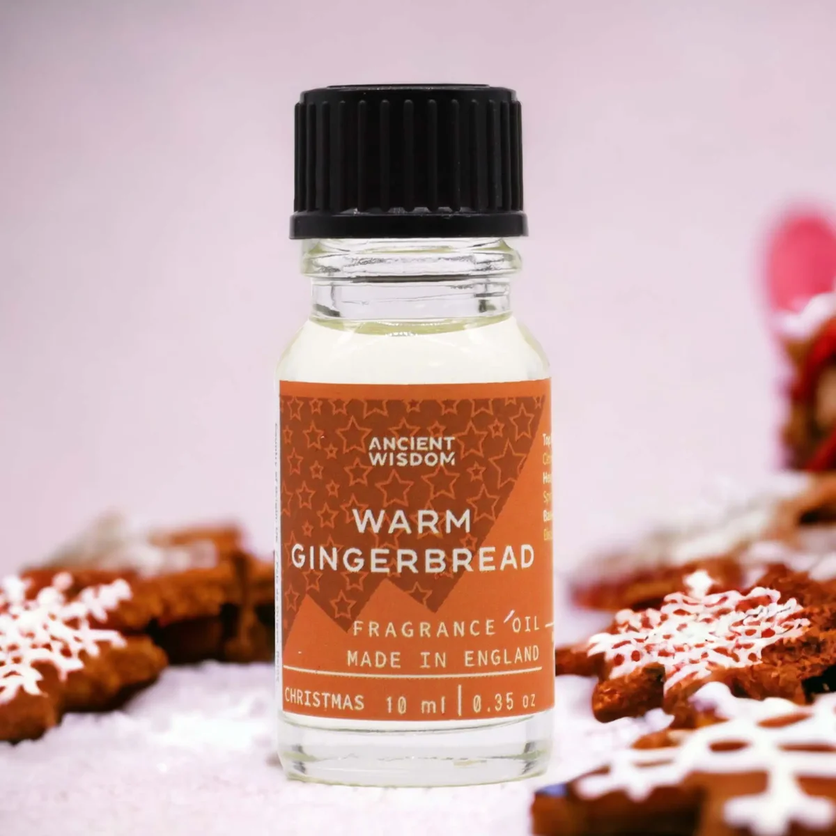 Small 10ml bottle of warm gingerbread scented oil with amber liquid and a white cap on a white background