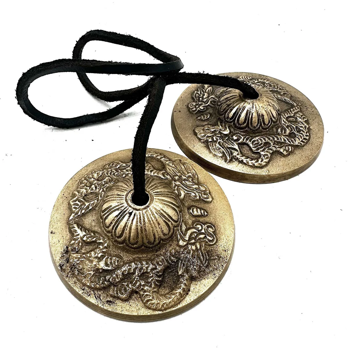 Tibetan Tingsha cymbals with dragon design, approximately 7.4cm in diameter on a wooden surface