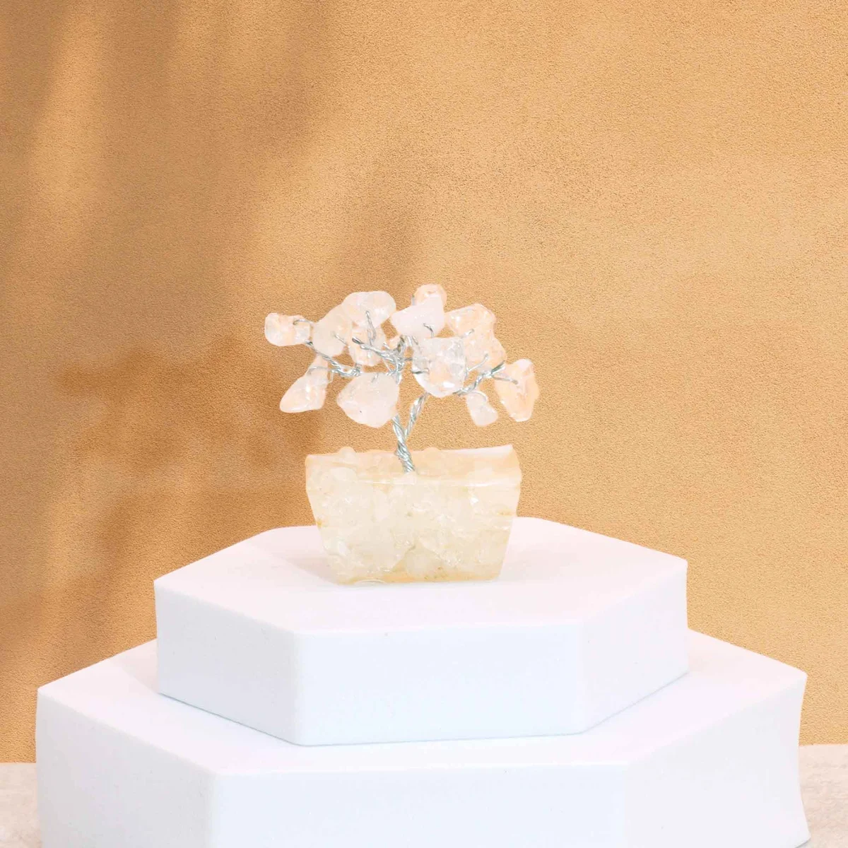 Mini gemstone tree with 15 rock quartz stones on a white orgonite base ornament against a plain background