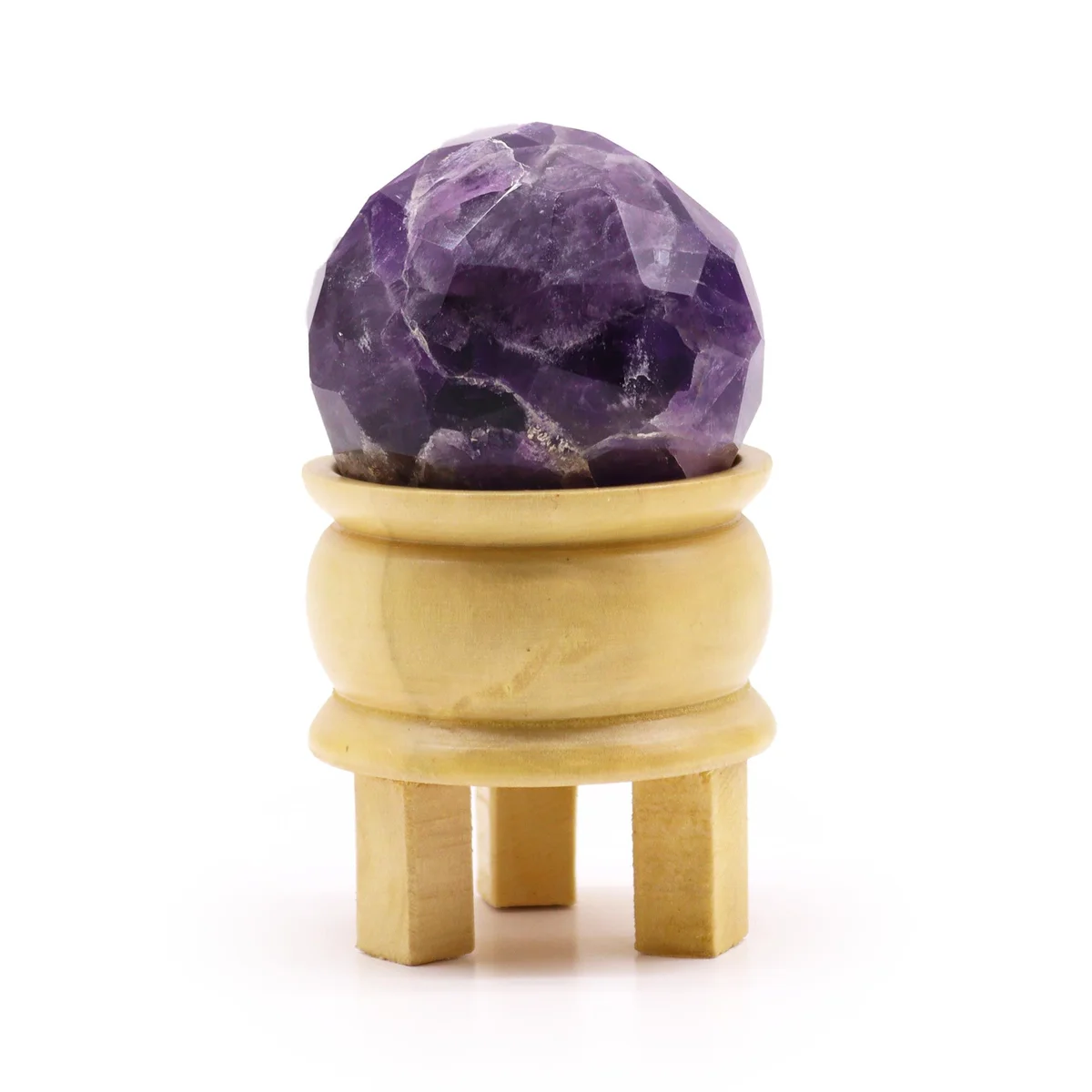 Faceted amethyst healing ball resting on a black stand against a white background