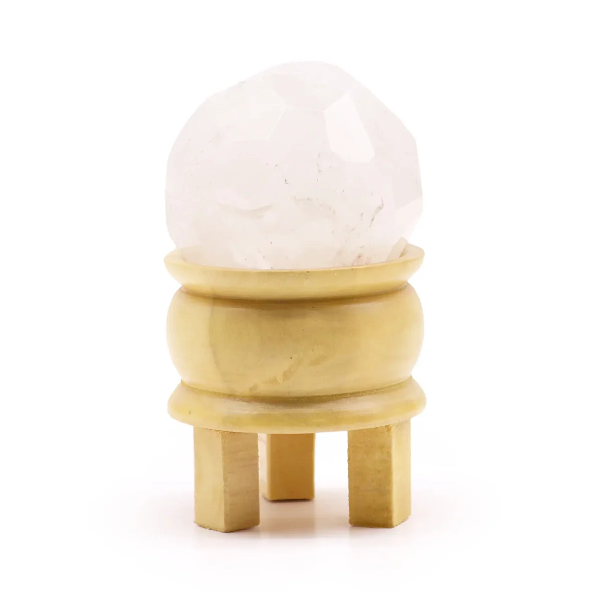 Faceted rock quartz ball resting on a wooden stand against a white background