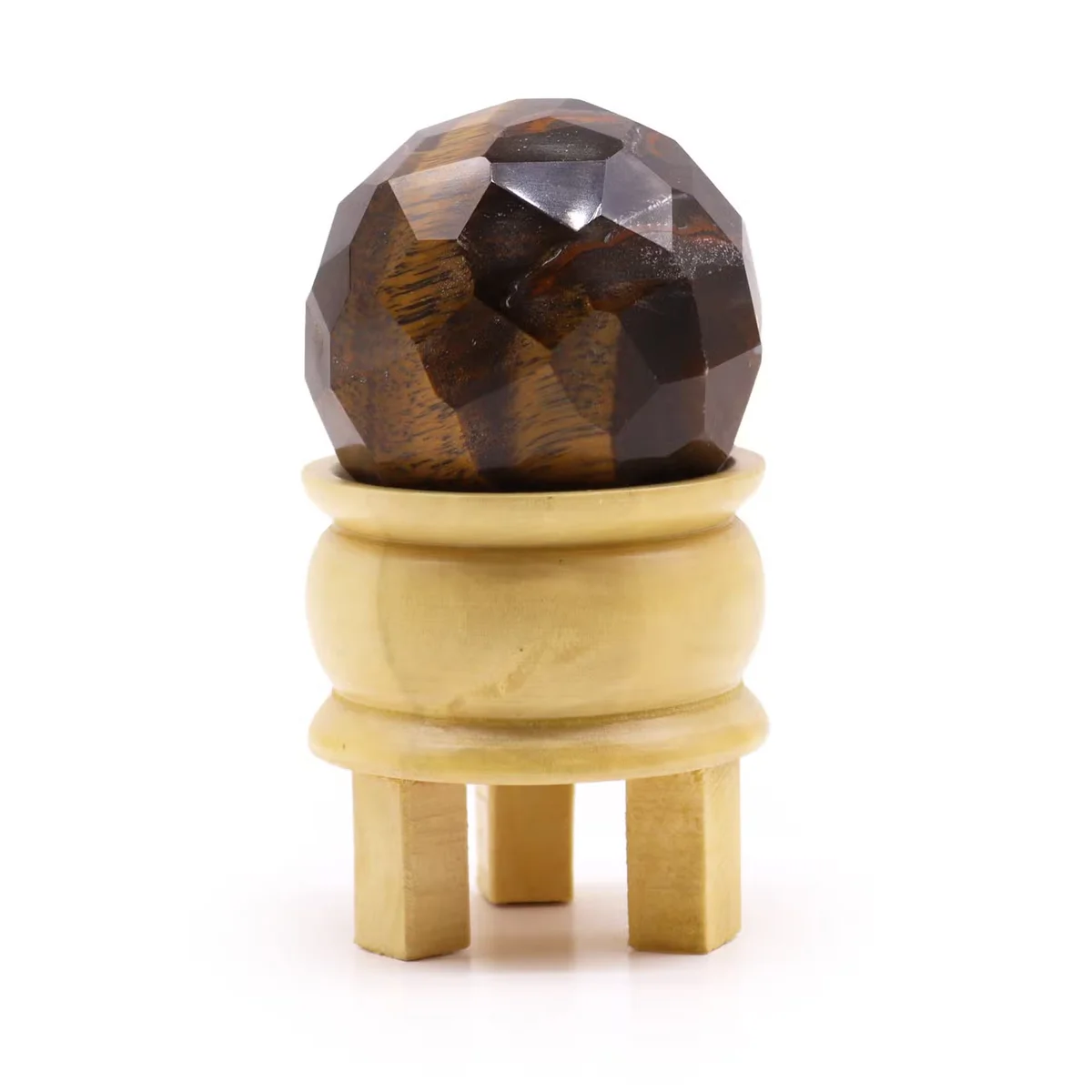Faceted tigereye healing ball resting on a black stand, showcasing its polished brown and gold stone surface tigereye decor piece