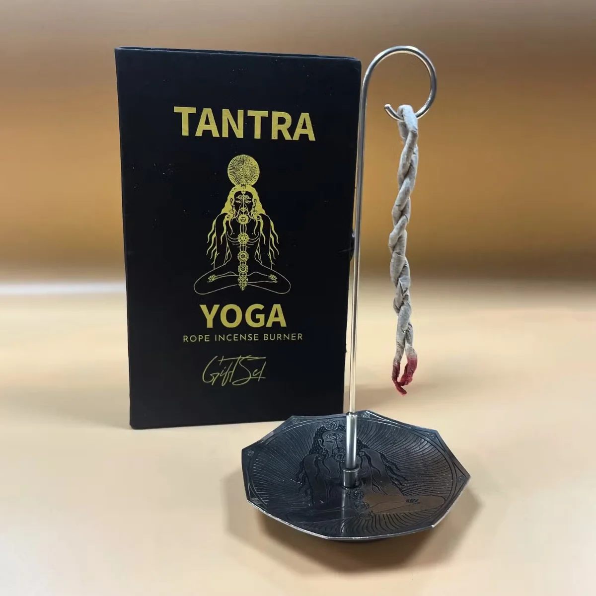 Silver plated decorative incense holder with lit rope incense stick from Tantra Yoga set on white background