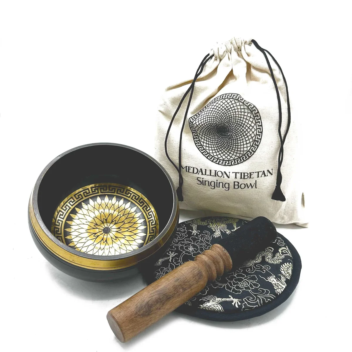 14cm hand beaten engraved singing bowl with round medallions in a gift set displayed on a wooden surface