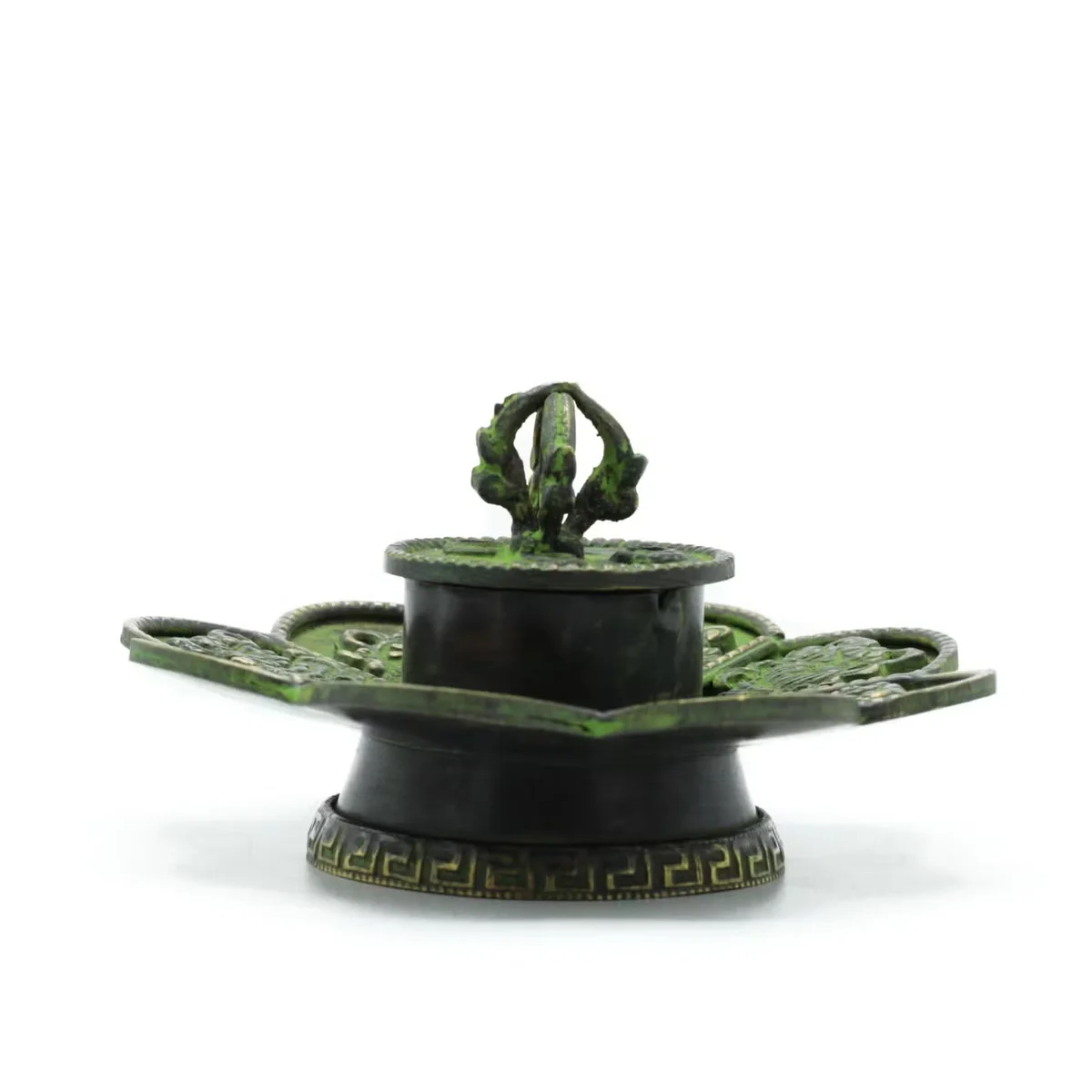 Brass verdigris cone incense holder with Tibetan Eight Symbols design, shown from angled side view on white background