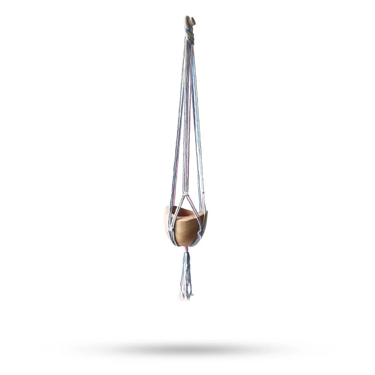 Macrame pot holder in pastel tones hanging in a bathroom, showcasing macrame bathroom decor.