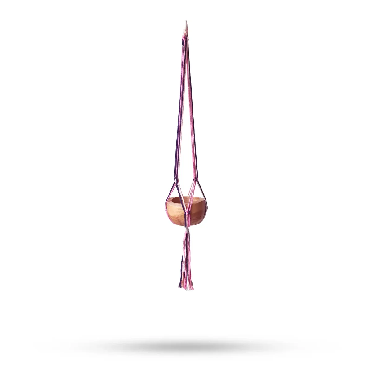 Pastel tones macramé pot holder draped over a medium pot in a living room, pastel tones decor.