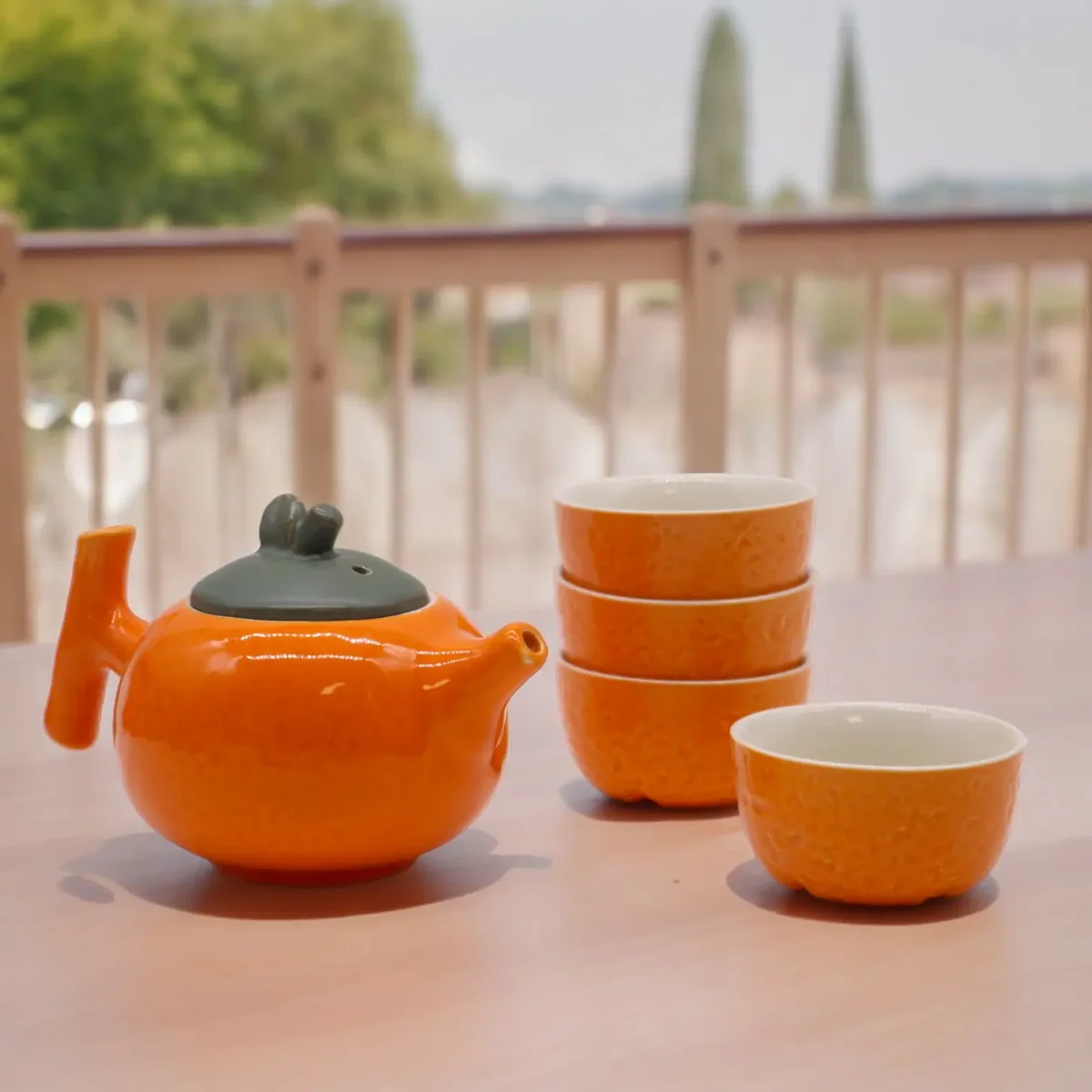 Orange herbal teapot set with pot and four matching cups, displayed against neutral background