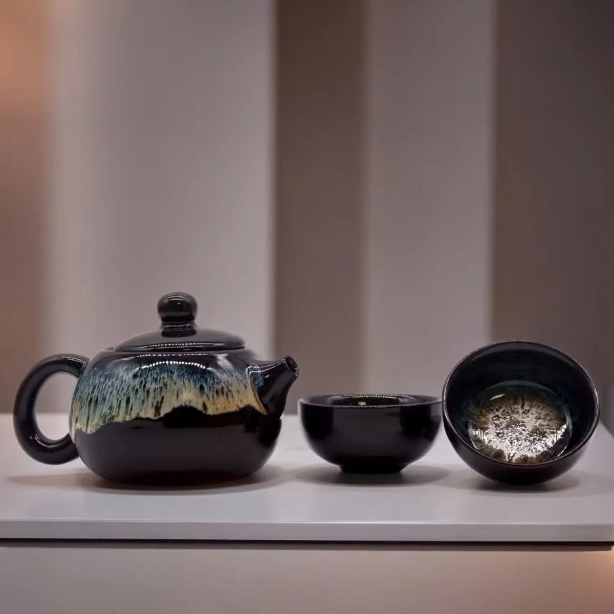 Black teapot with matching cups displayed on a table.