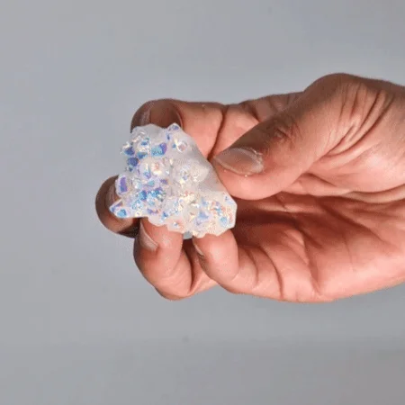 Small enhanced quartz crystal with iridescent colors, known as aura angel quartz, on a white background
