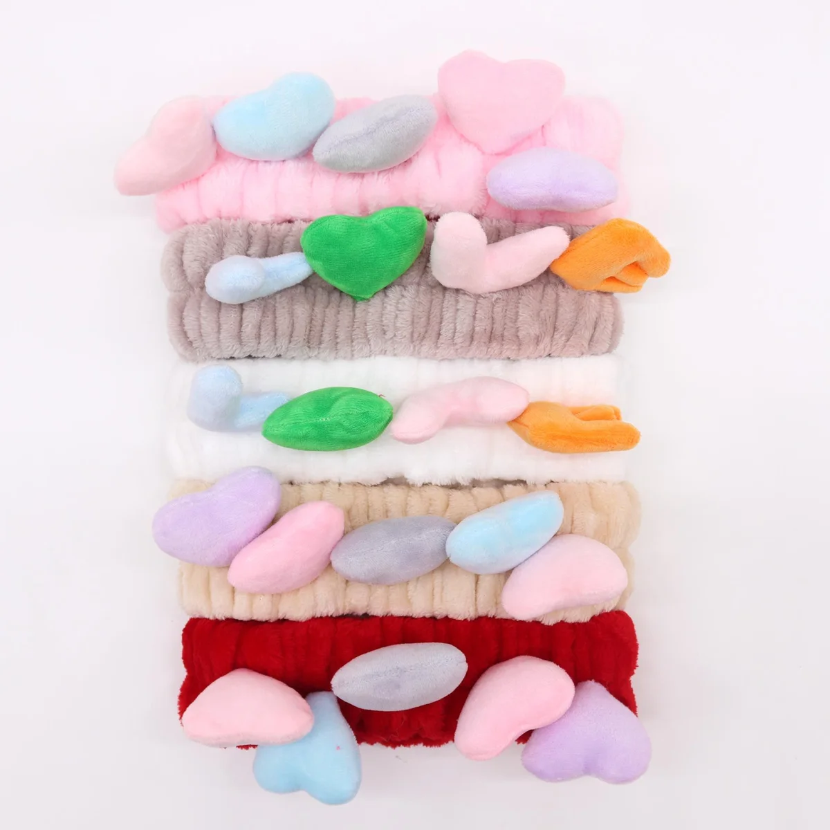 Assorted cute makeup headbands featuring love and heart designs in soft pastel colors on a white background
