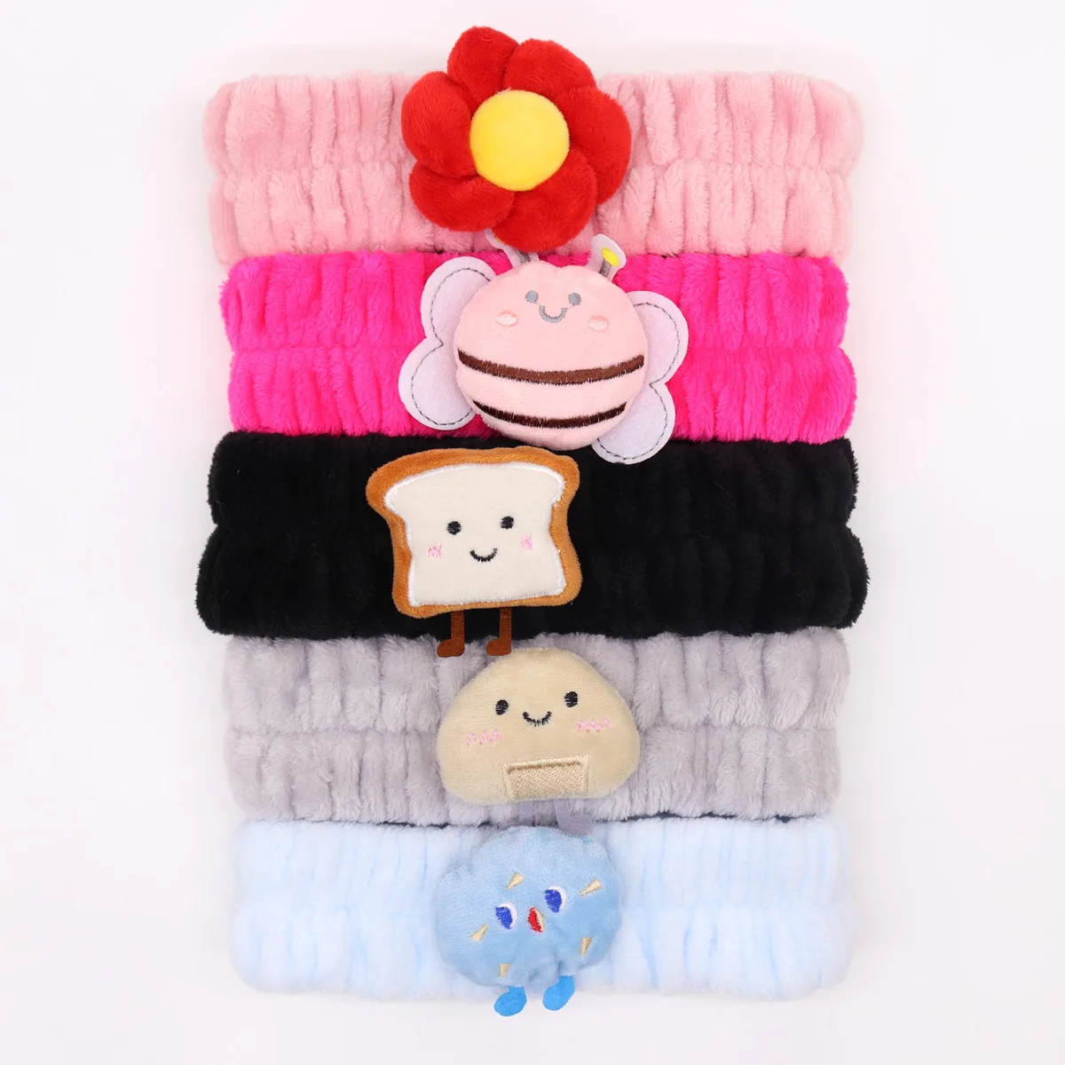 Assorted makeup headbands featuring cute Toast & Friends designs in various colors and patterns on a white background