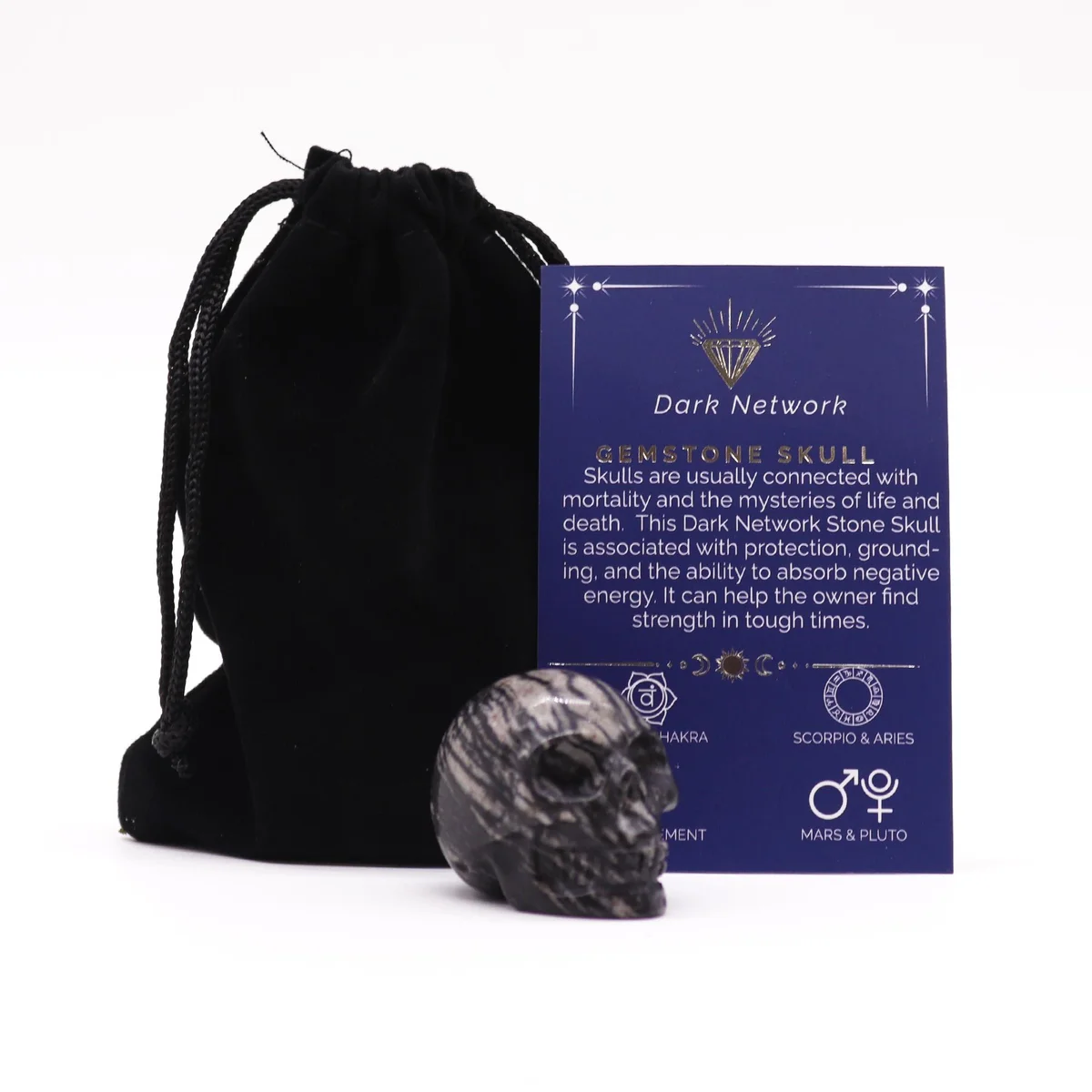 Small gemstone skull carved from dark network stone with intricate details on a white background