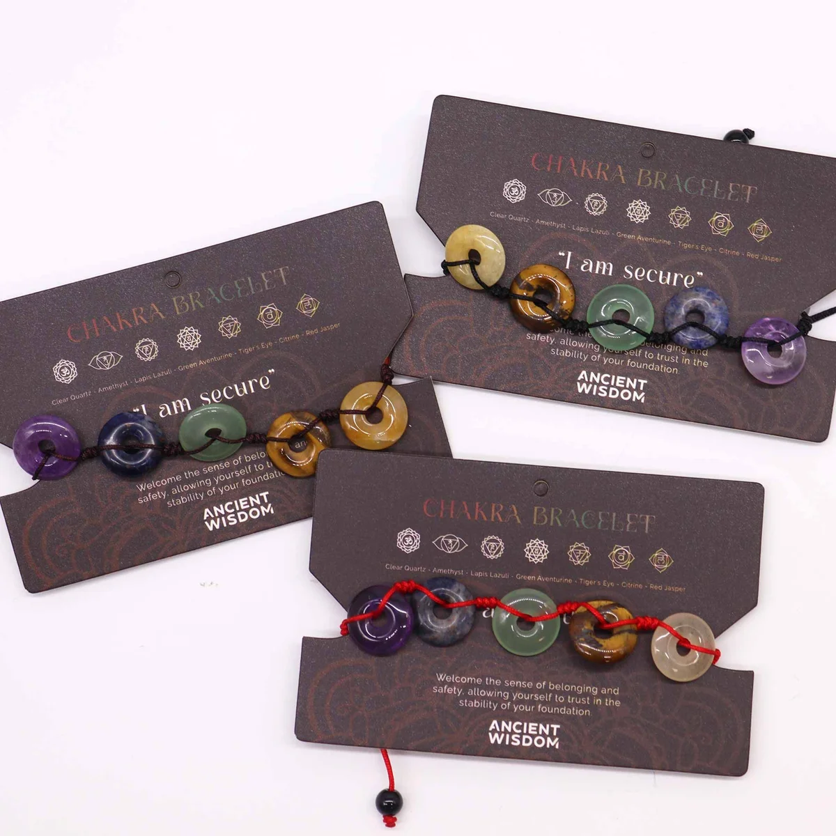 Chakra string bracelet featuring large donut-shaped beads in various colors on a black string