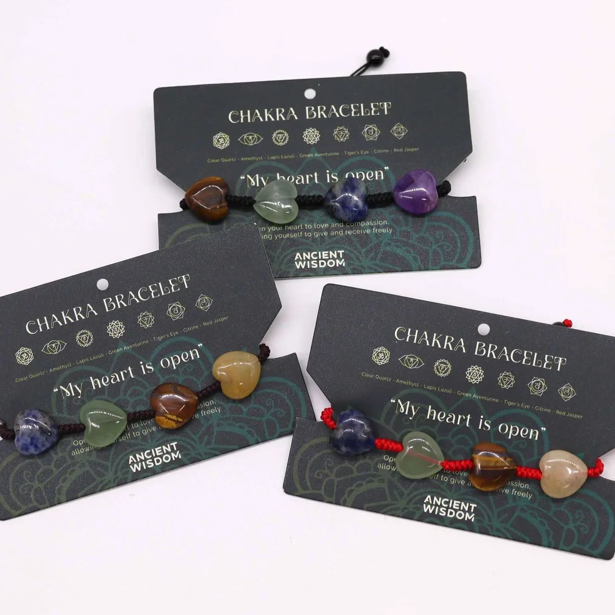 Chakra string hearts bracelet featuring colorful beads on a red adjustable cord against a white background