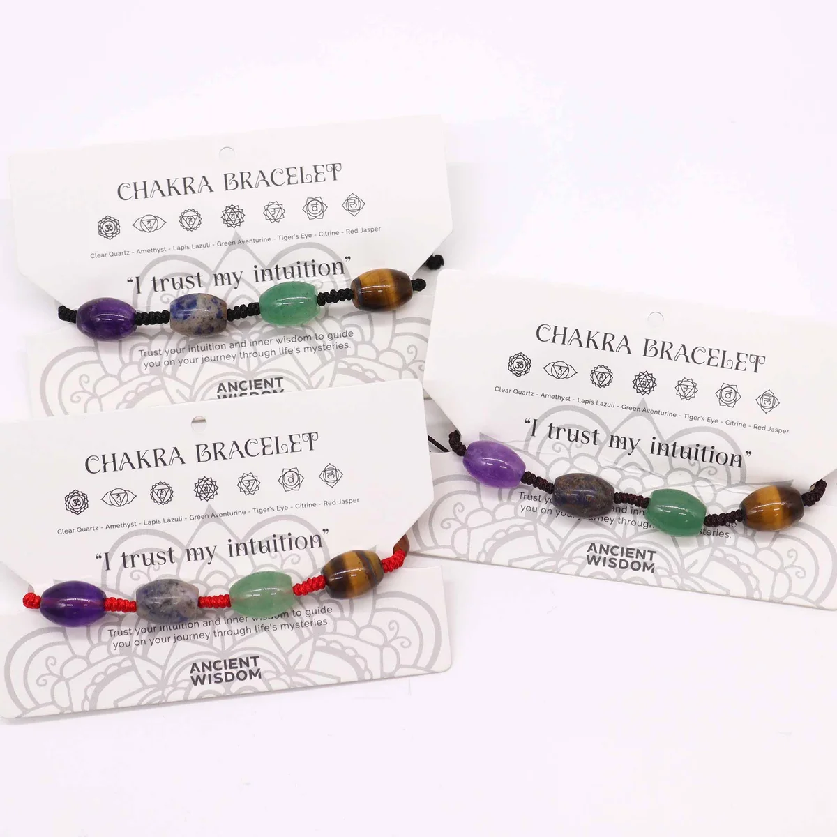Close-up of colorful chakra beads on a string bracelet against a plain background