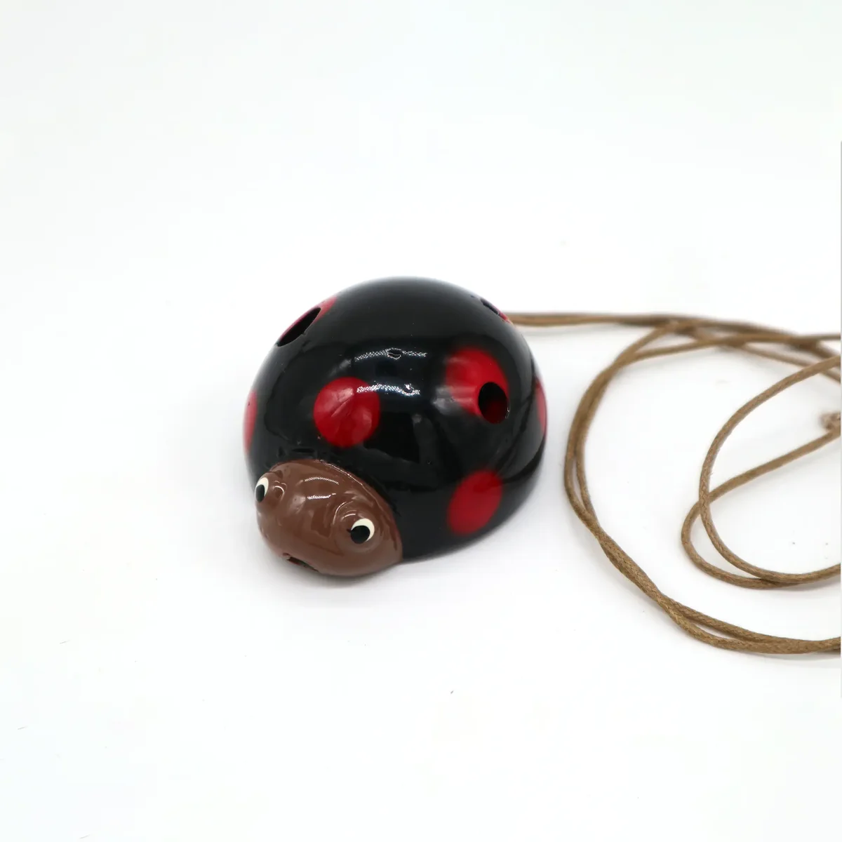 Red ceramic ladybird ocarina musical animal with holes for playing notes on a white background