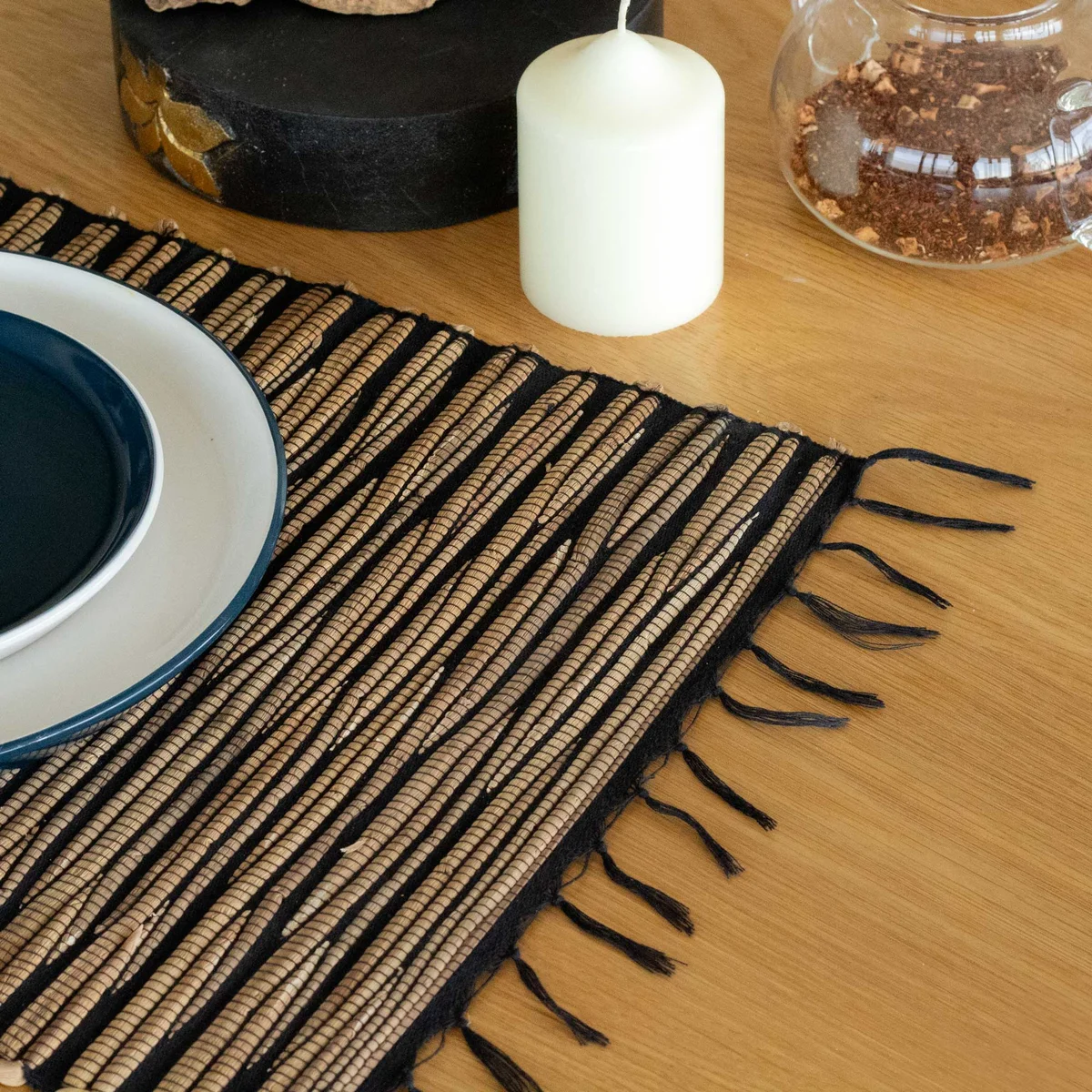 Black tiger placemat made from natural water hyacinth with decorative fringe on edges laid flat on surface