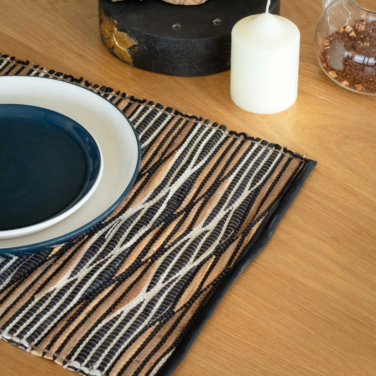 Black and white waves patterned natural placemat made from water hyacinth fibers on a white background