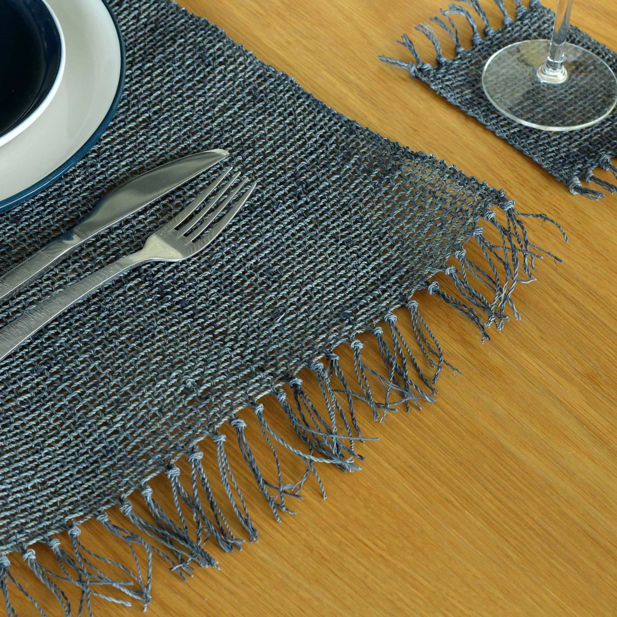 Charcoal fringe placemat made of natural seagrass with textured woven design and decorative edges on white background