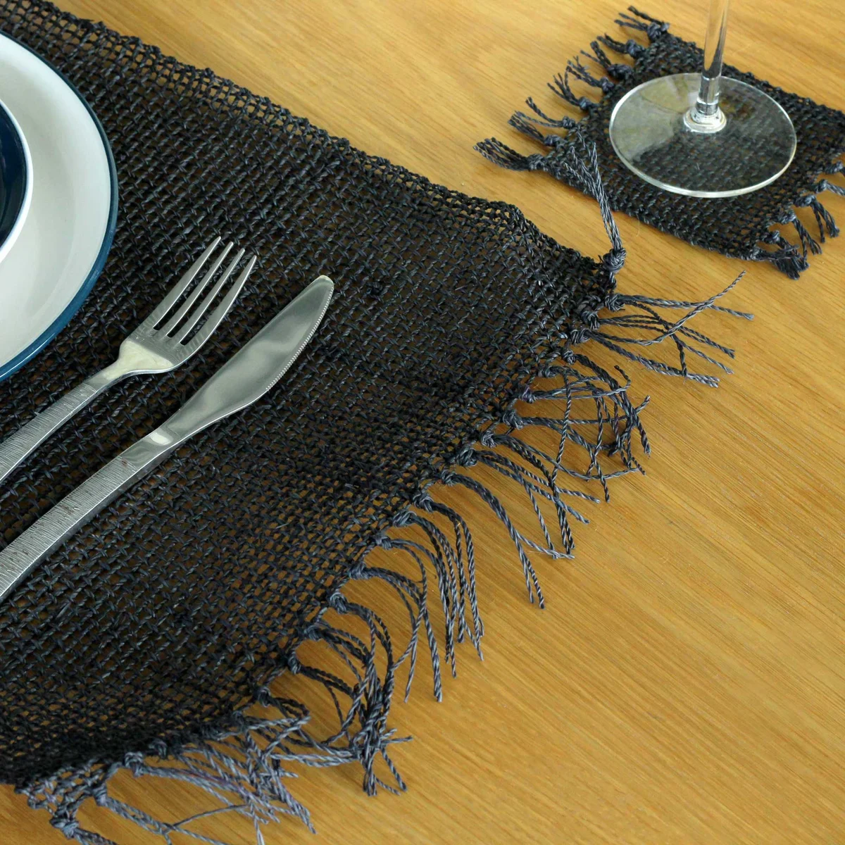 Seagrass placemat black with natural woven texture and fringe edges laid flat on white background