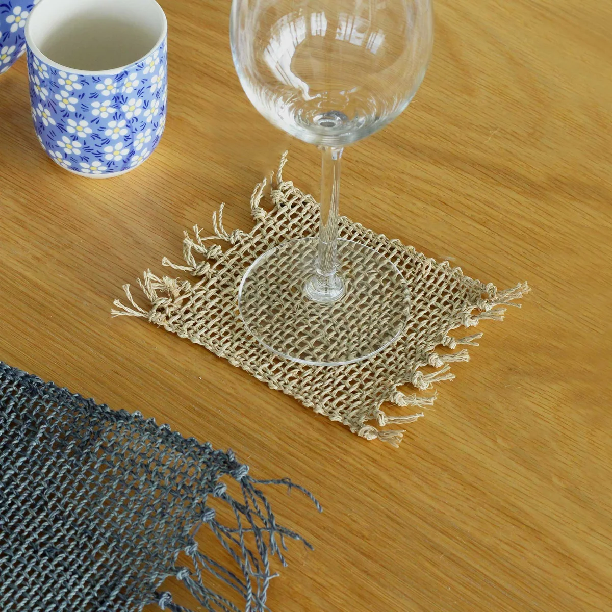 Set of 4 natural seagrass coasters set with fringe edges arranged on a flat surface