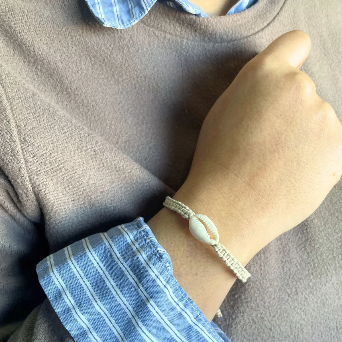 Assorted handmade friendship bracelets featuring cowrie shell charms on colorful woven bands