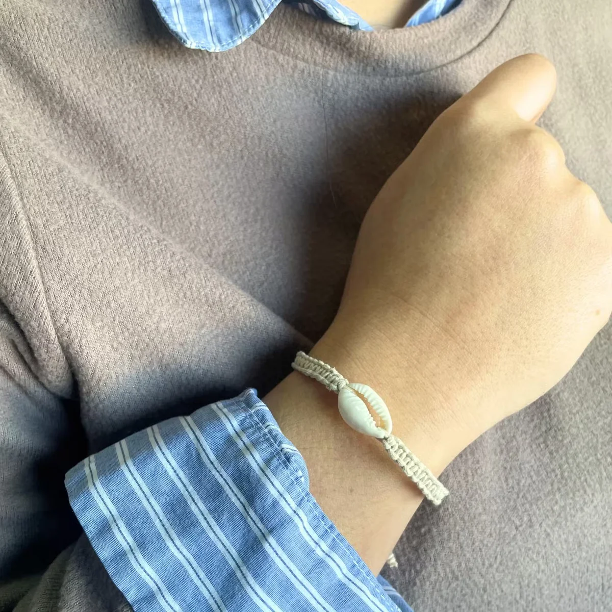 Three handmade shell bracelets featuring cowrie shells in assorted colors on a white background