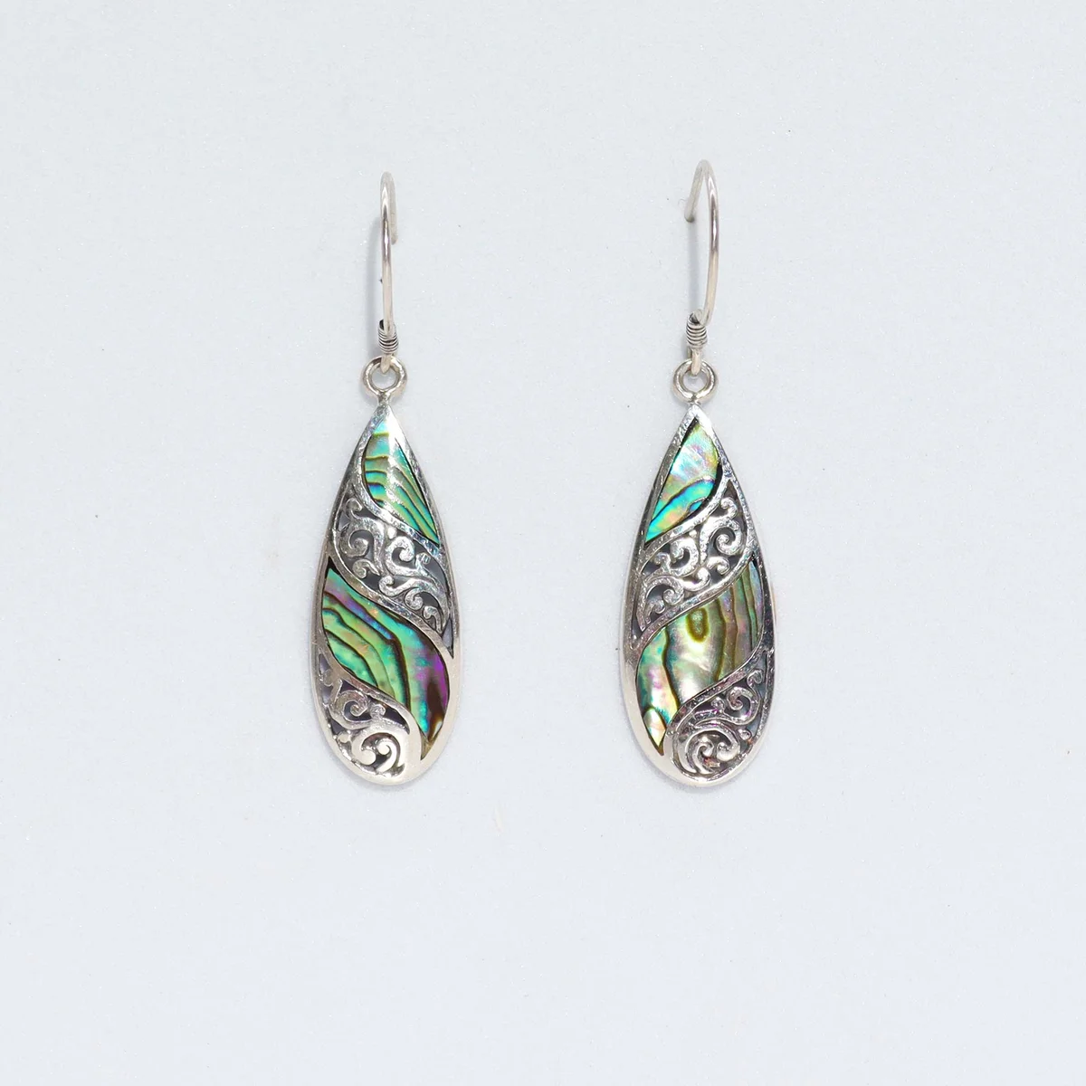 Long teardrop abalone earrings with shell and silver accents on plain background