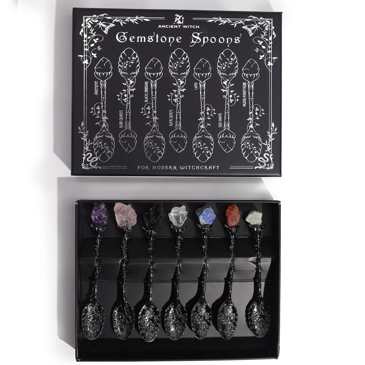 Set of seven dark silver crystal spoons with gemstone crystal spoons displayed on a decorative surface.