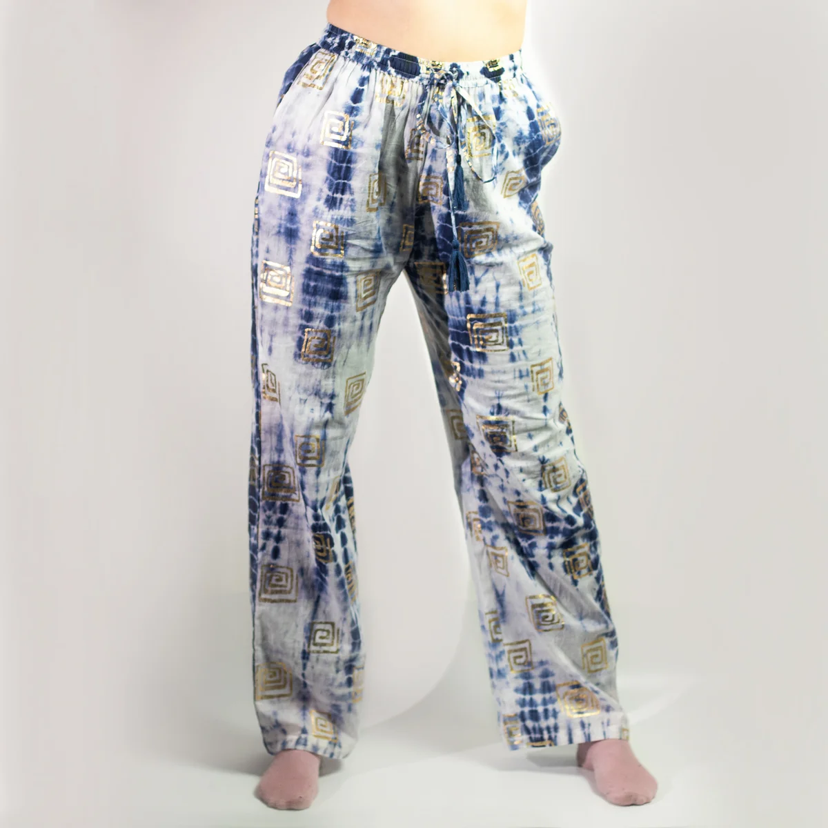 Nomad blue lounge trousers featuring tie‑dye pattern and gold Greek motif on airy denim.