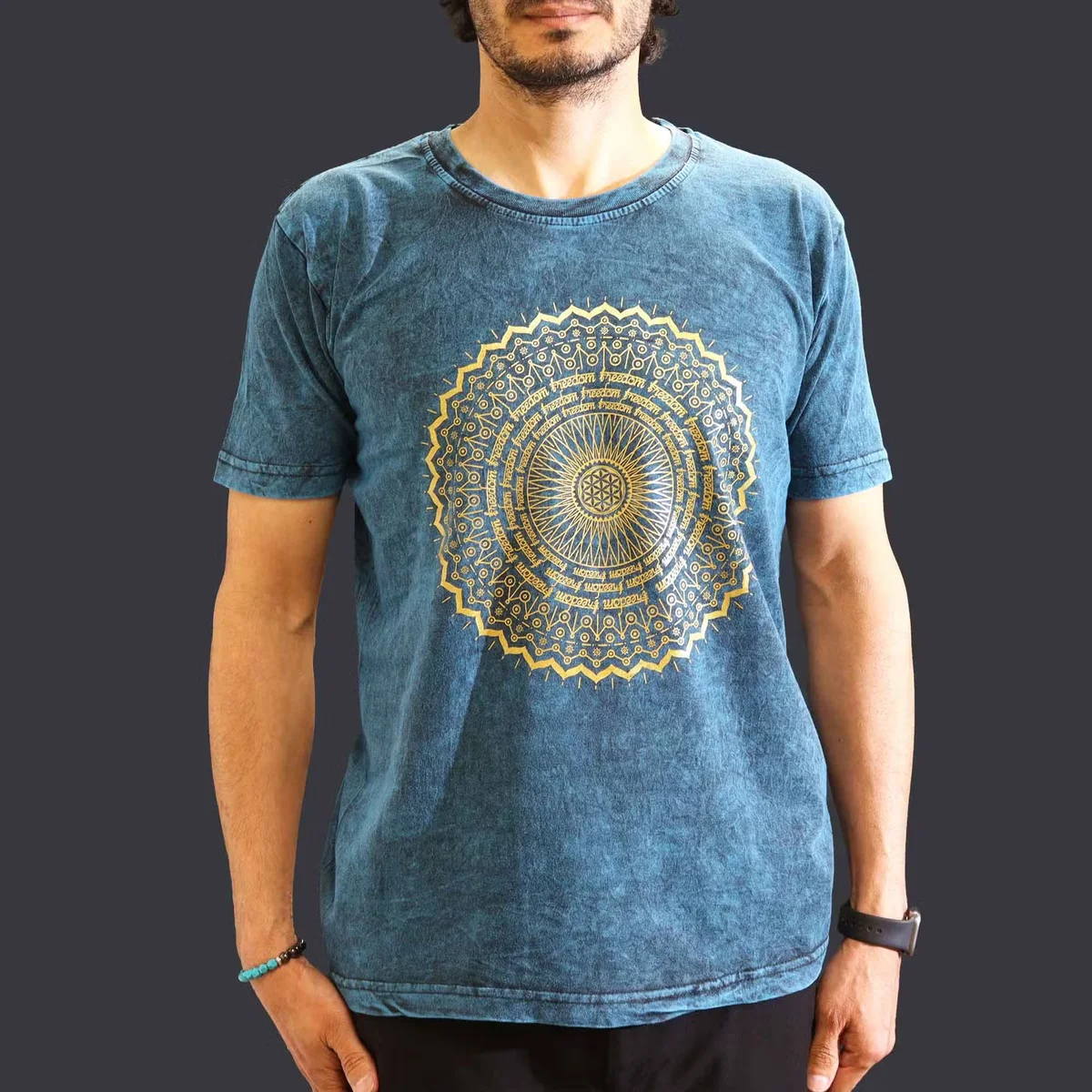 Casual blue t-shirt with medium stone washed effect and mandala design on front, laid flat on white background