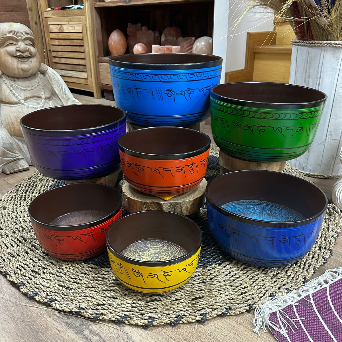 Set of seven large chakra meditation bowls in varying sizes, displayed upright on a wooden stand