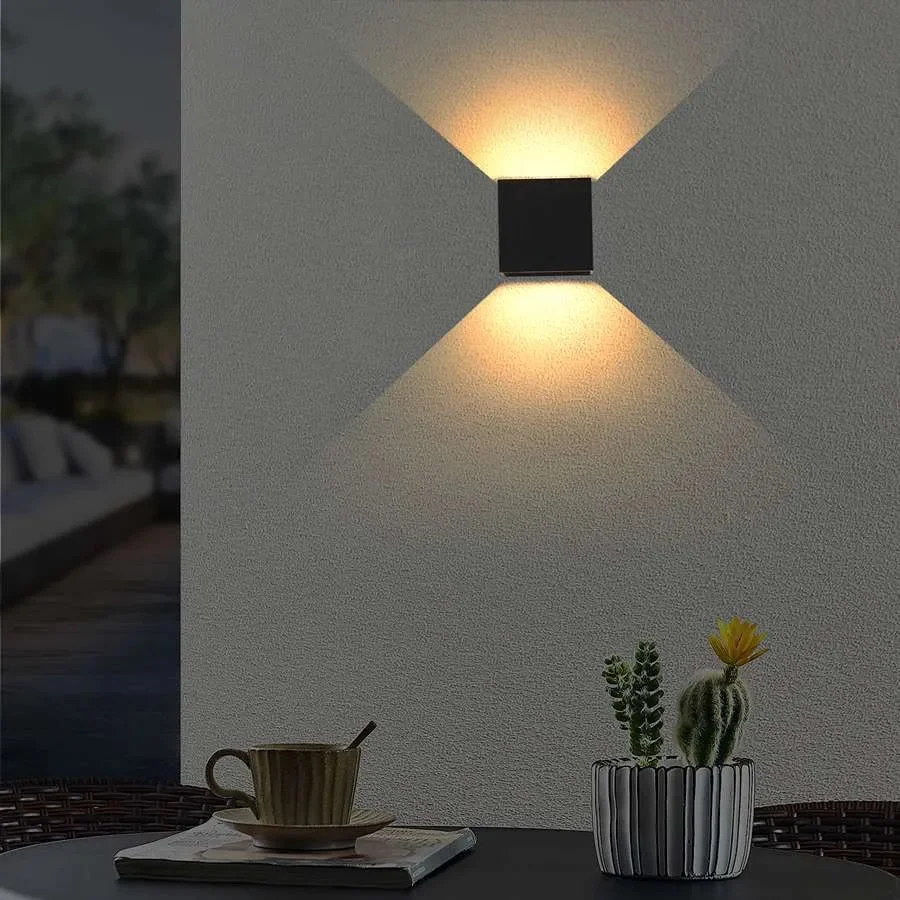 Black square outdoor wall light with PIR sensor, emitting warm white LED lights, mounted on a wall at night