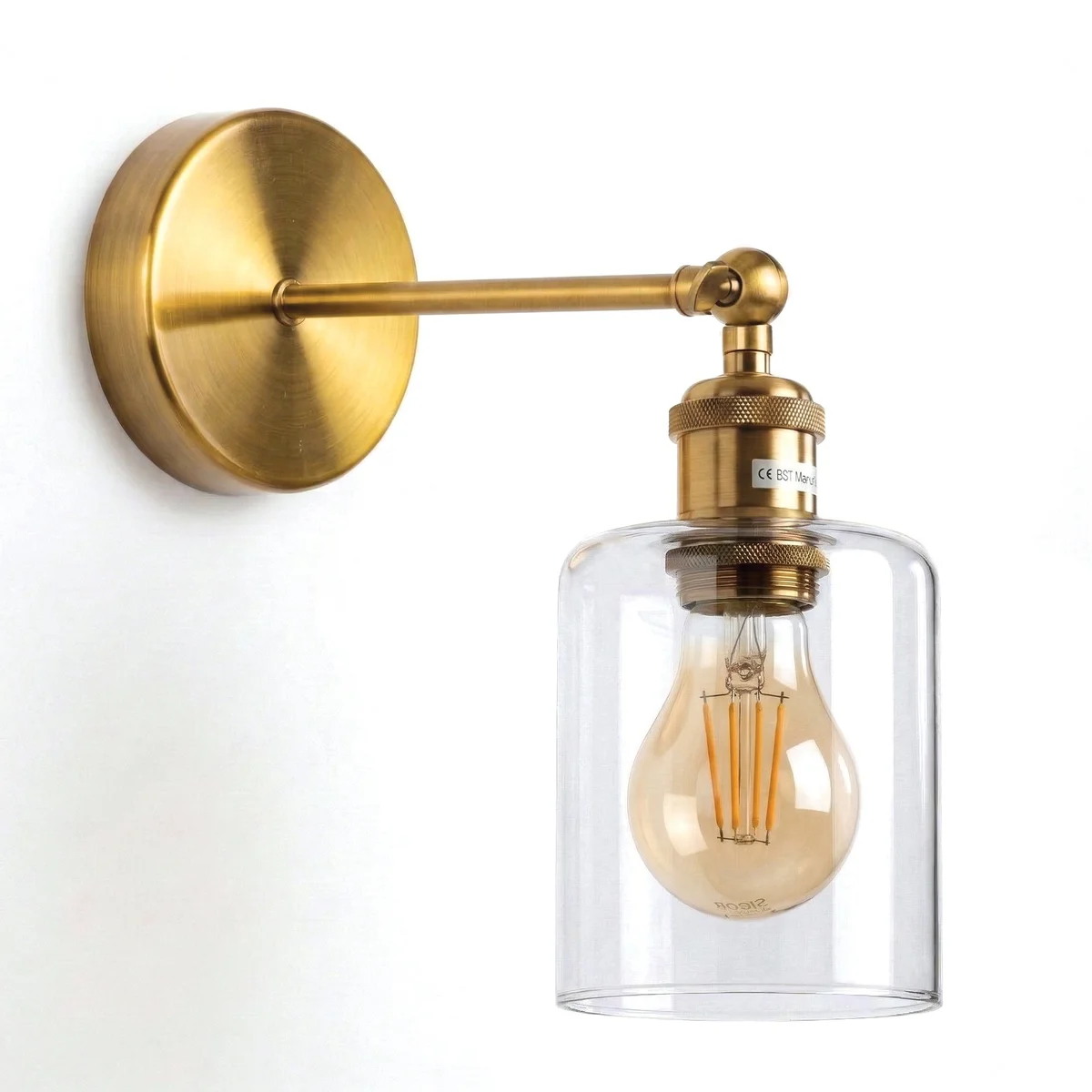 Yellow brass wall light with adjustable 180° swing arm and clear glass cylinder shade, mounted on a wall indoors