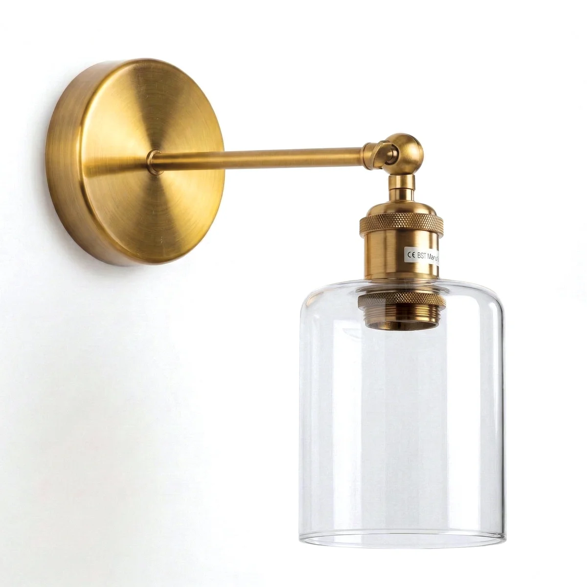 Vintage brass wall sconce with adjustable arm and clear glass cylinder shade mounted on a wall, showing warm ambient light