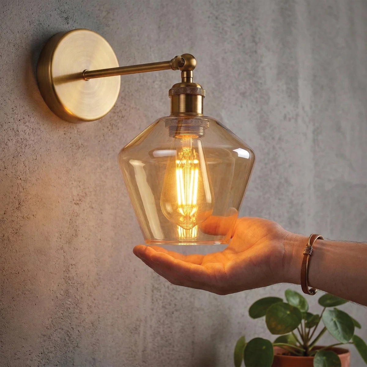 Vintage brass wall sconce with adjustable swing arm and amber faceted glass shade mounted on a wall