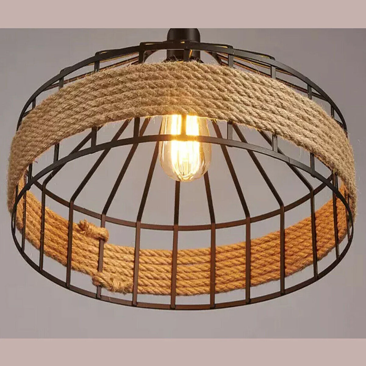 Large hemp rope pendant light with metal cage hanging above wooden table in rustic café setting