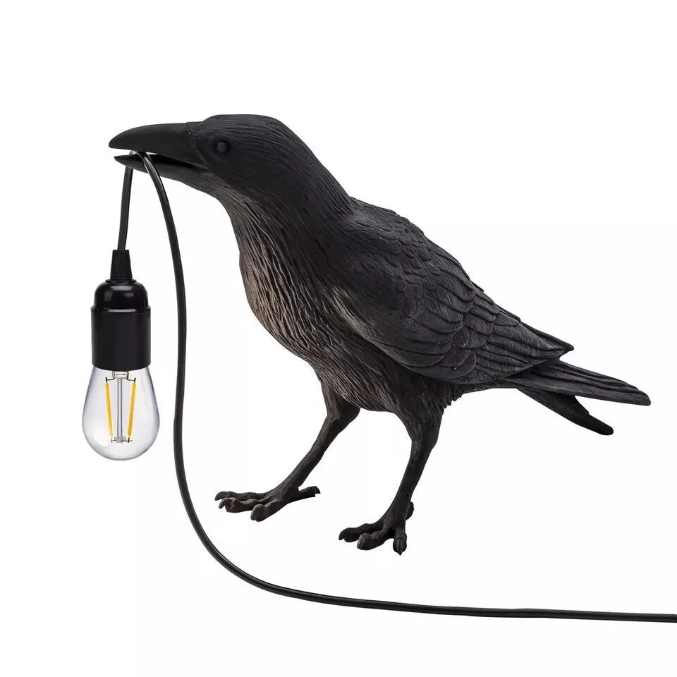 Black resin crow table lamp with E27 bulb, modern bird-shaped design, shown on wooden surface against white background