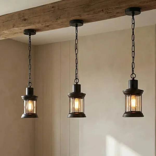 Three vintage industrial glass pendant lights with black metal cages hanging in a row against a white background