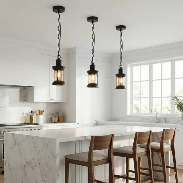 Three black metal cage industrial pendant lights with clear cylindrical glass shades hanging in a row