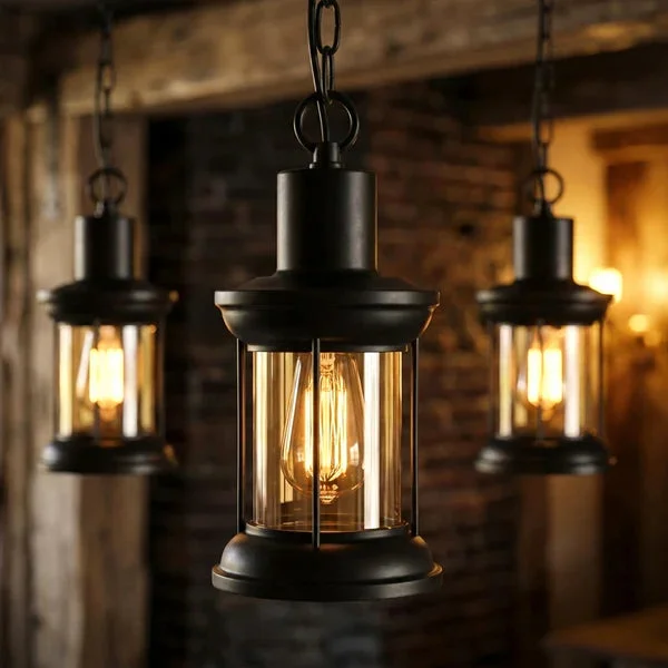 Three vintage industrial glass pendant lights with black metal cages hanging in a row over a kitchen island