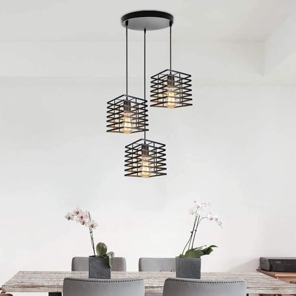 Three black metal cage adjustable pendant lights hanging at different heights against a white background