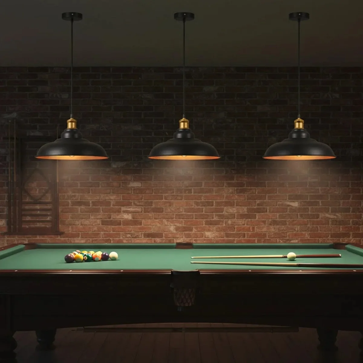 Three black pendant light fittings with metal shades and gold interiors hanging in a row, vintage style