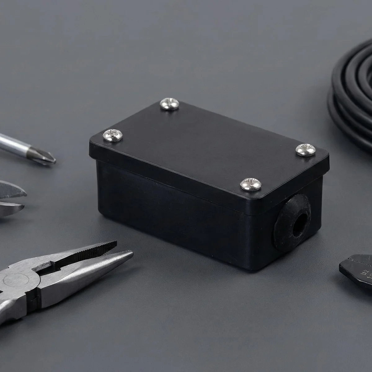 Black IP44 electrical wiring junction box with 3-core terminal block and mounting screws on white background