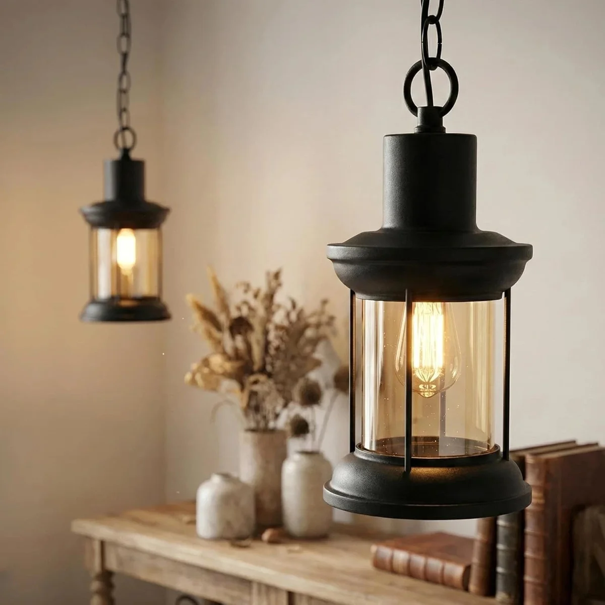 Adjustable black metal cage lamp with clear glass dome pendant hanging from a black chain against a white background