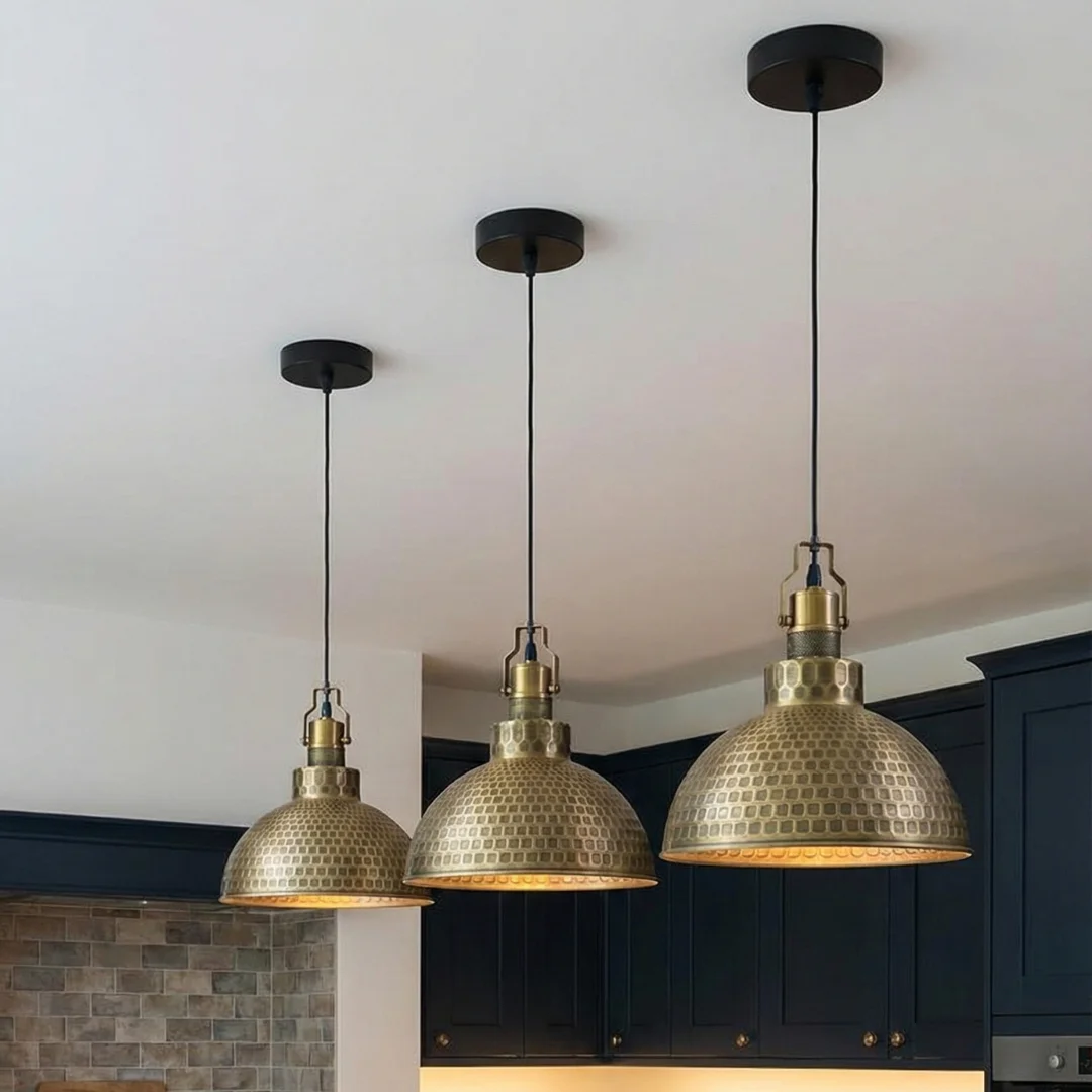 Green brass hammered pendant light with metal dome shade and adjustable cable hanging against white background