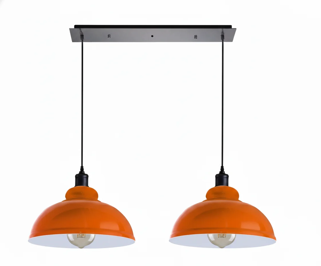 Two metal dome dimmable ceiling lights with adjustable cords in brushed brass finish hanging over a dining table