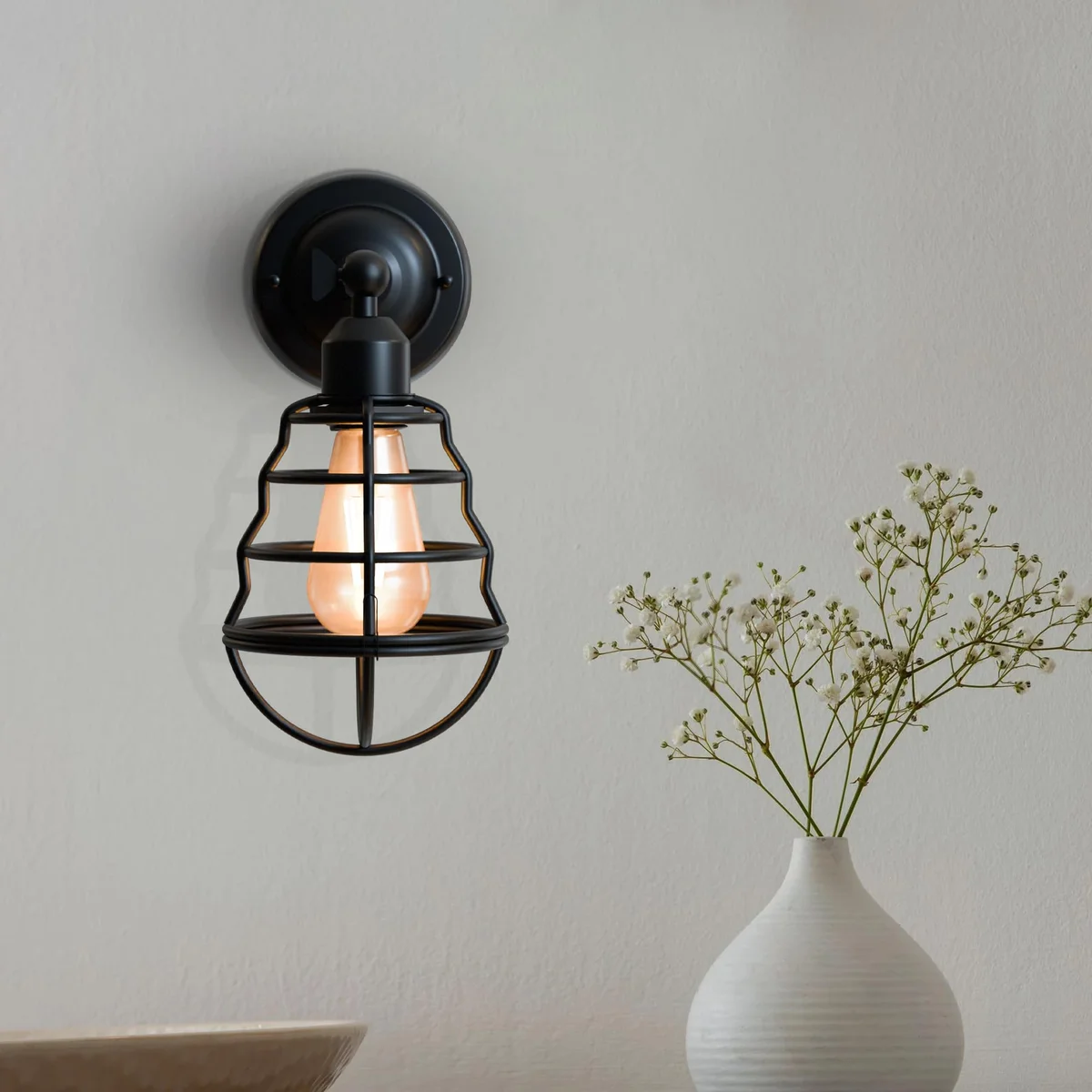 Adjustable industrial metal wall light with balloon-shaped cage and vintage style sconce design in dimmable finish